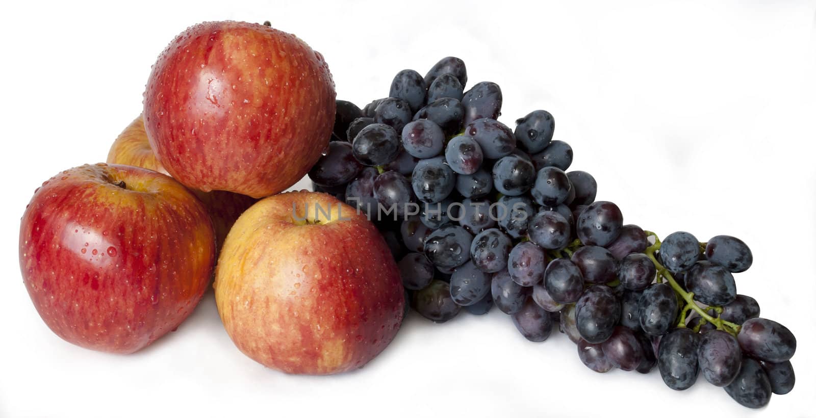 
three apples and a bunch of grapes, covered with drops of water