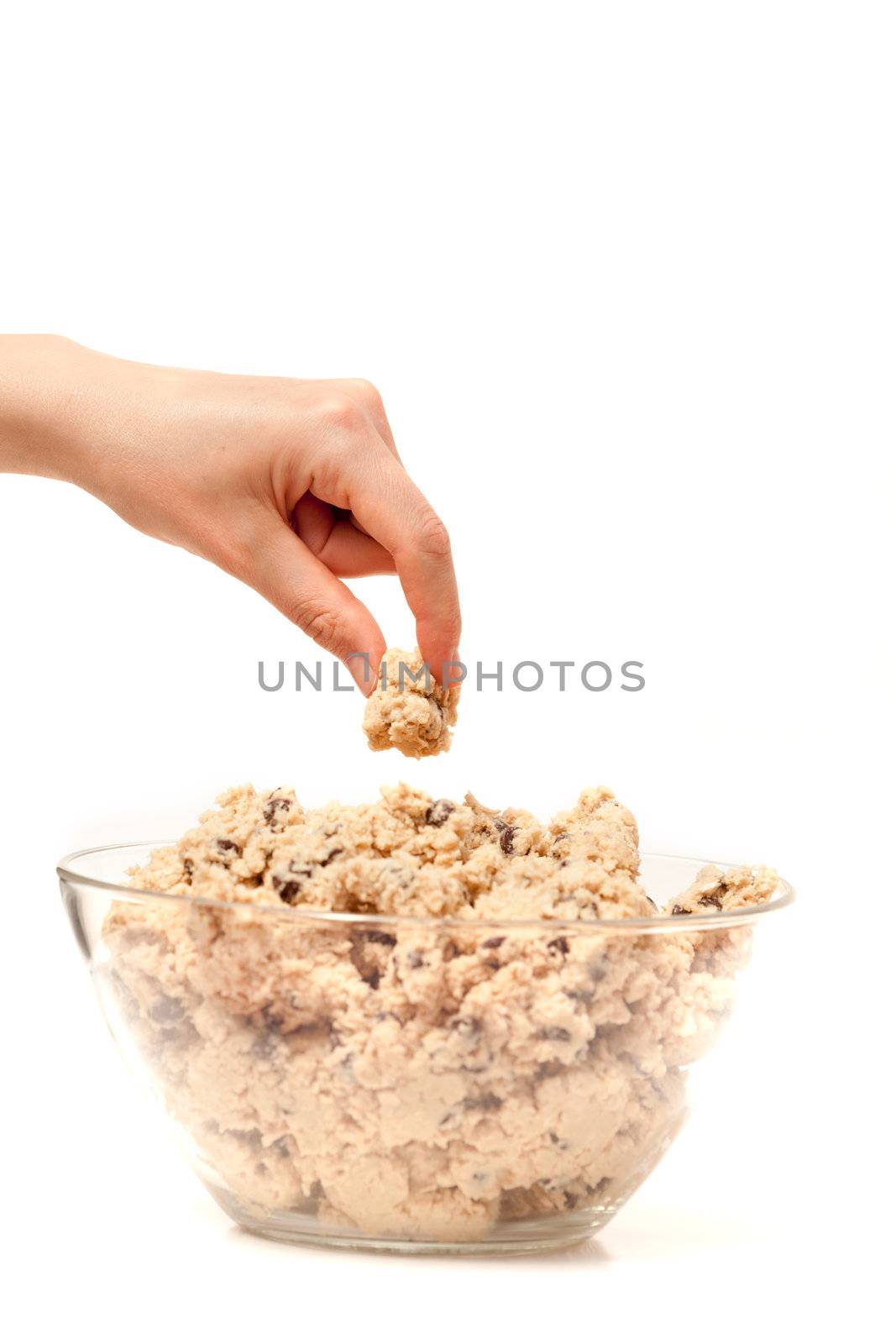A hand sneaking a taste test of cookie dough.