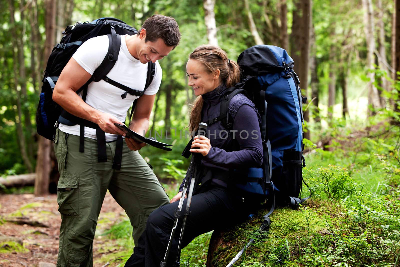 A couple with smiles looking at a map in the forest 