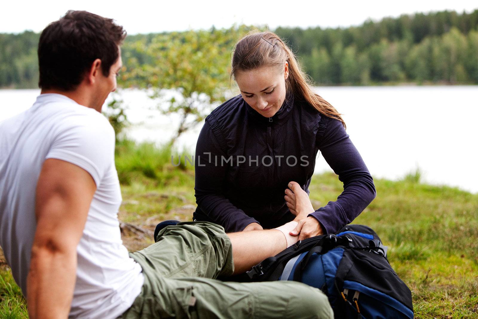 A woman applying an ankle bandage on a male camper