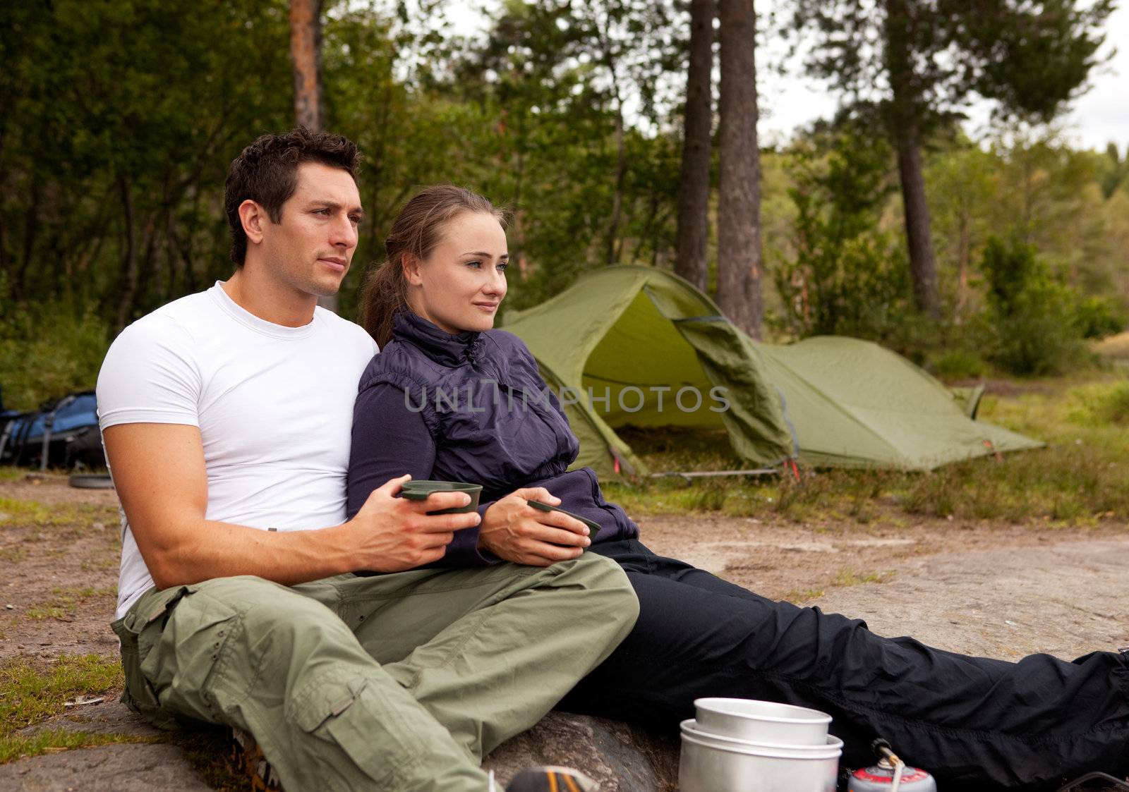 A couple sitting enjoying eachothers company while camping