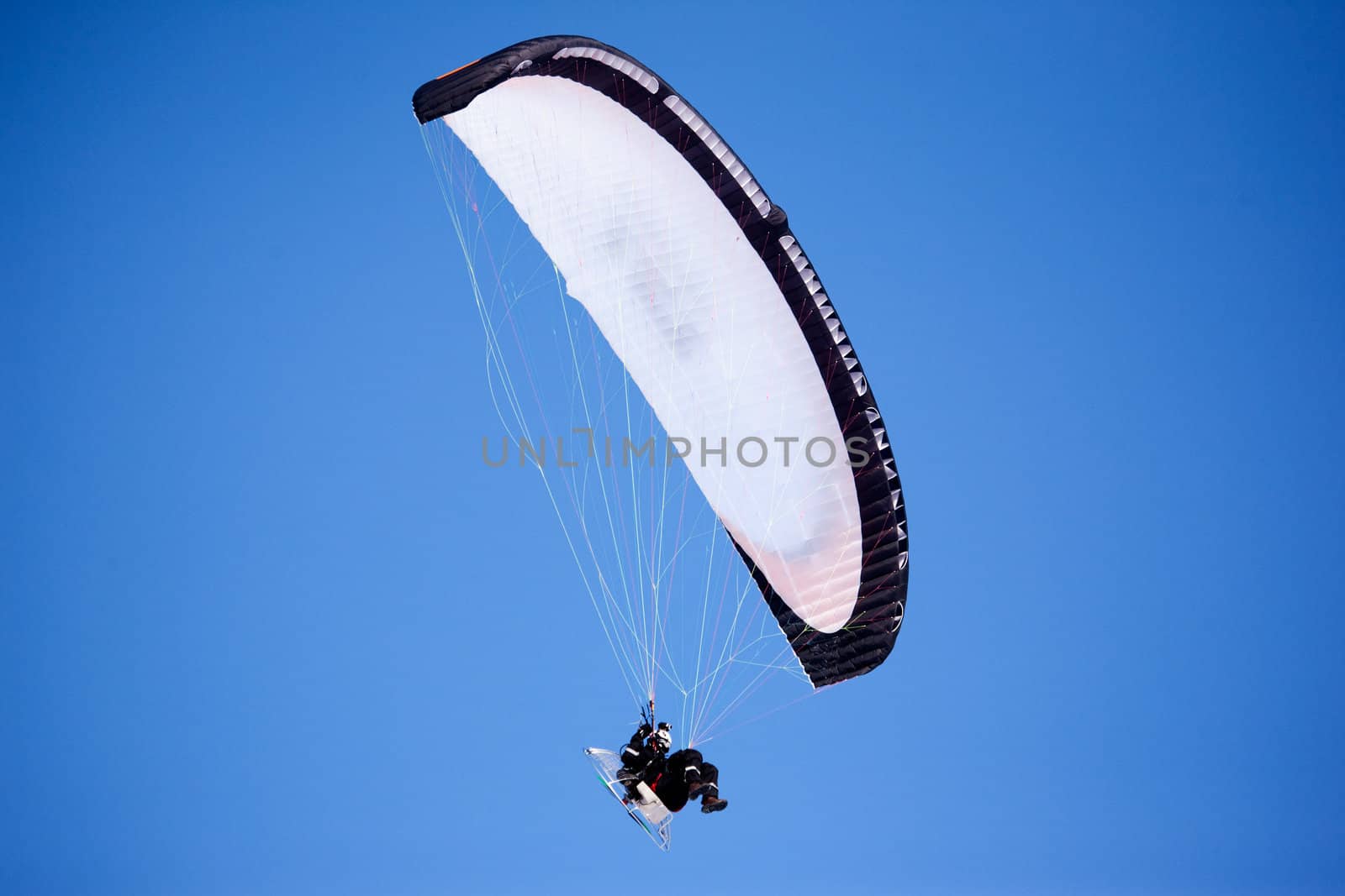 A paraglider isolated against a deep blue sky
