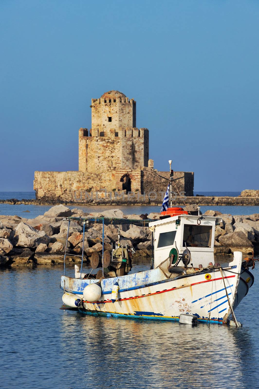 Picture of a fishing boat in front of the Methoni castle in southern Greece. 