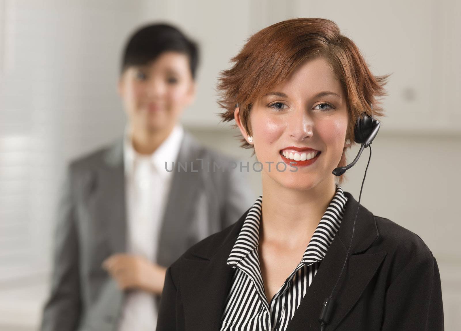 Pretty Red Haired Businesswoman and Colleague with Headset in Office Setting.