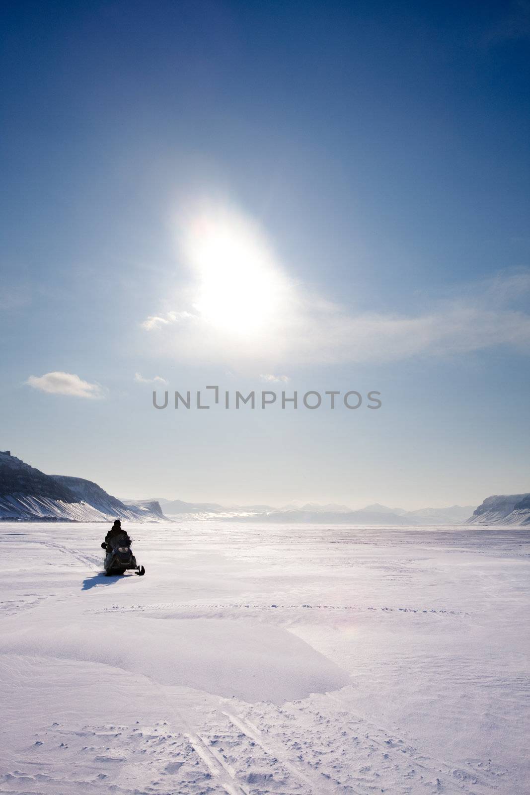 A snowmobile on frozen ice on a barren winter landscape