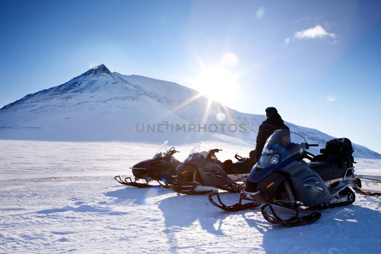 Three snowmobiles and a winter landscape with mountain