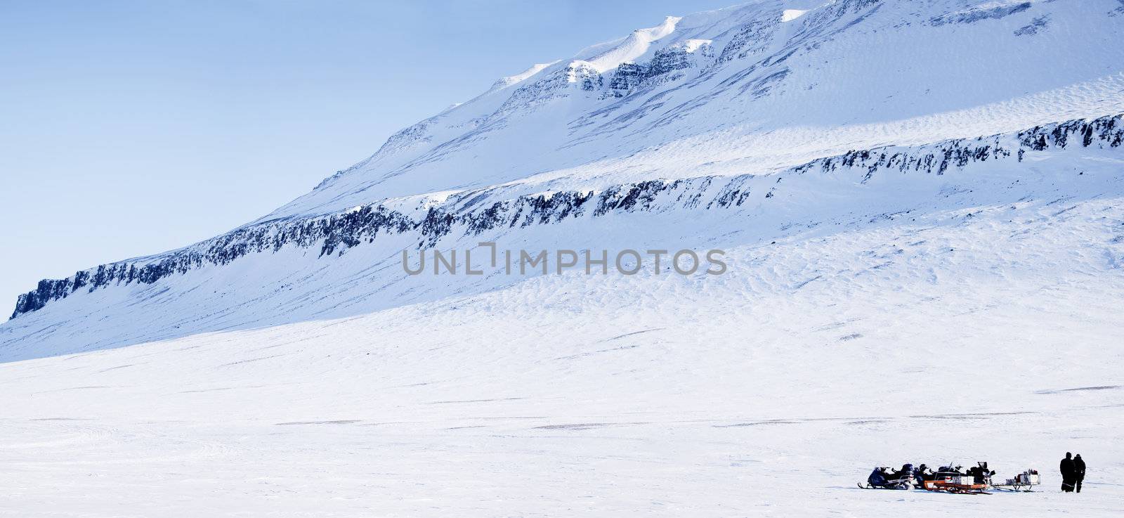 Three snowmobiles and a winter landscape with mountain