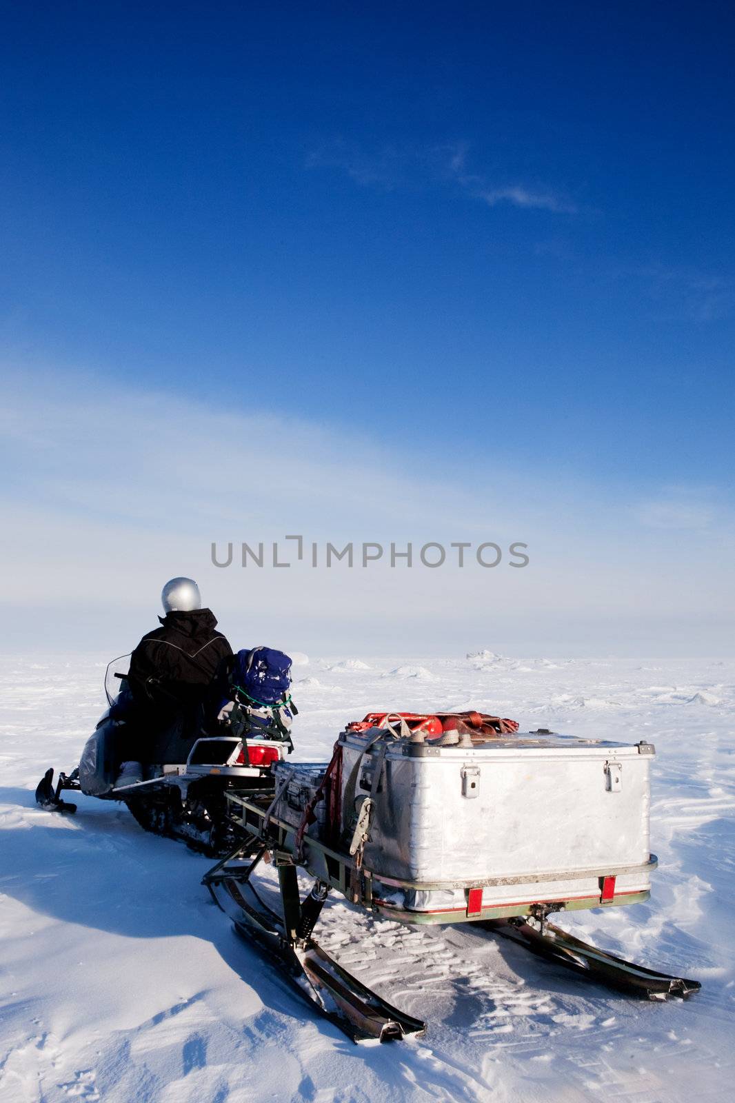 A man sitting on a snowmobile on a barren snow landscape