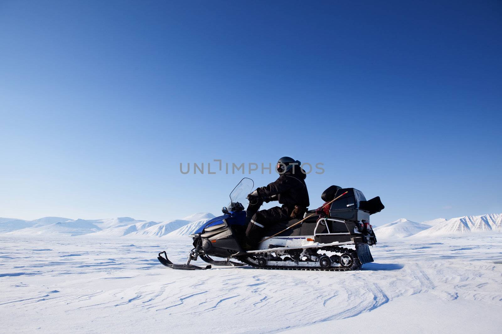 A snowmobile on a frozen lake against a winter landscape with mountains