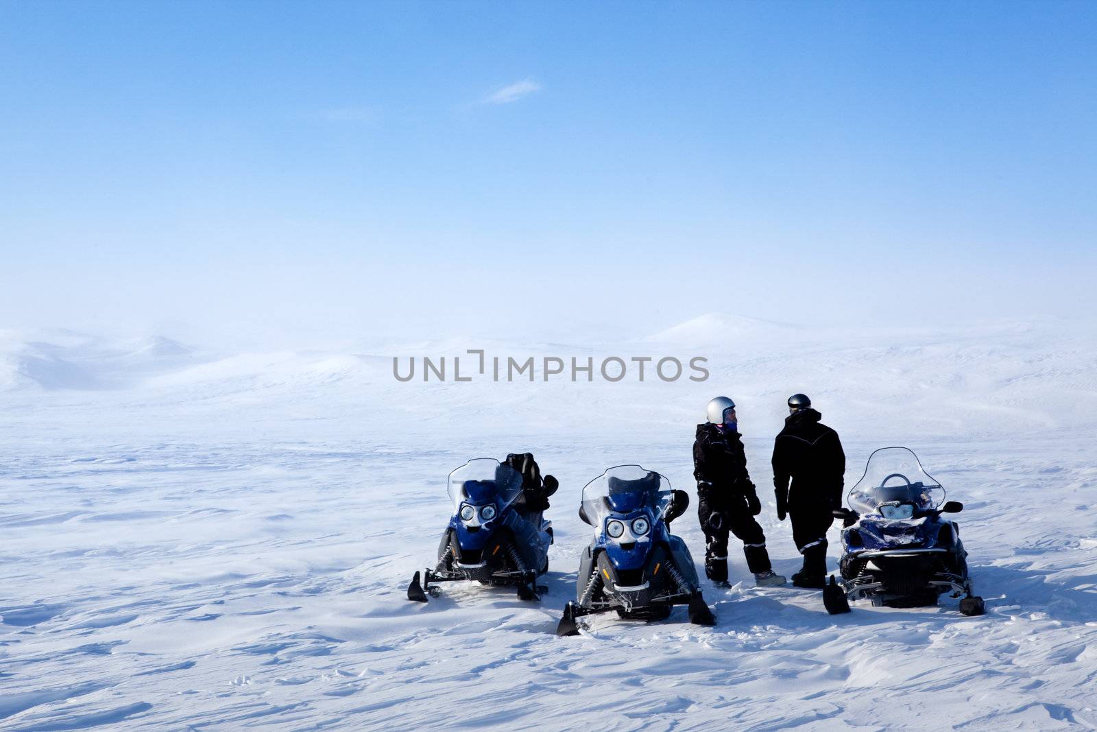 A barren winter landscape with a group of people on a snowmobile expedition