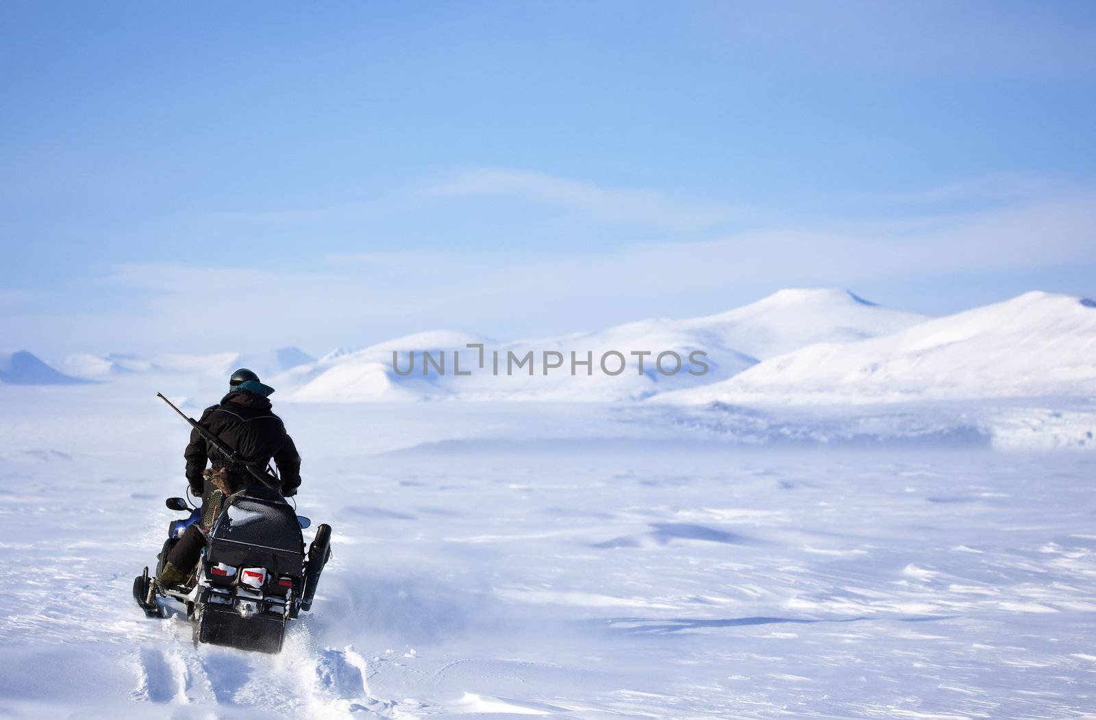 A winter landscape with a snowmobile travelling across frozen ice