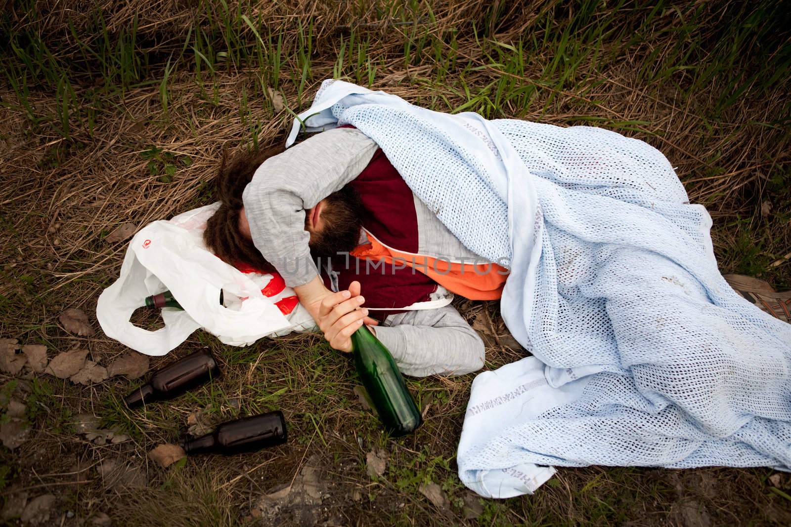 A homeless drunk person laying by the edge of the road