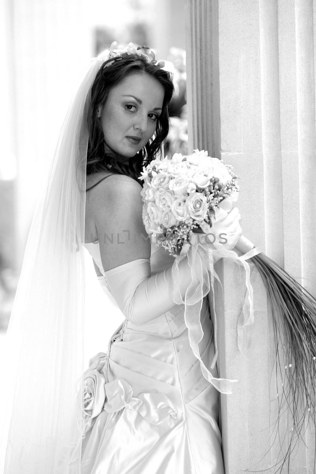 Side portrait of young bride holding bouquet of flowers.
