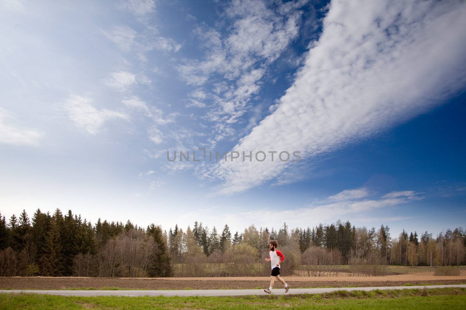 A runner with long hair and beard jogging in the country