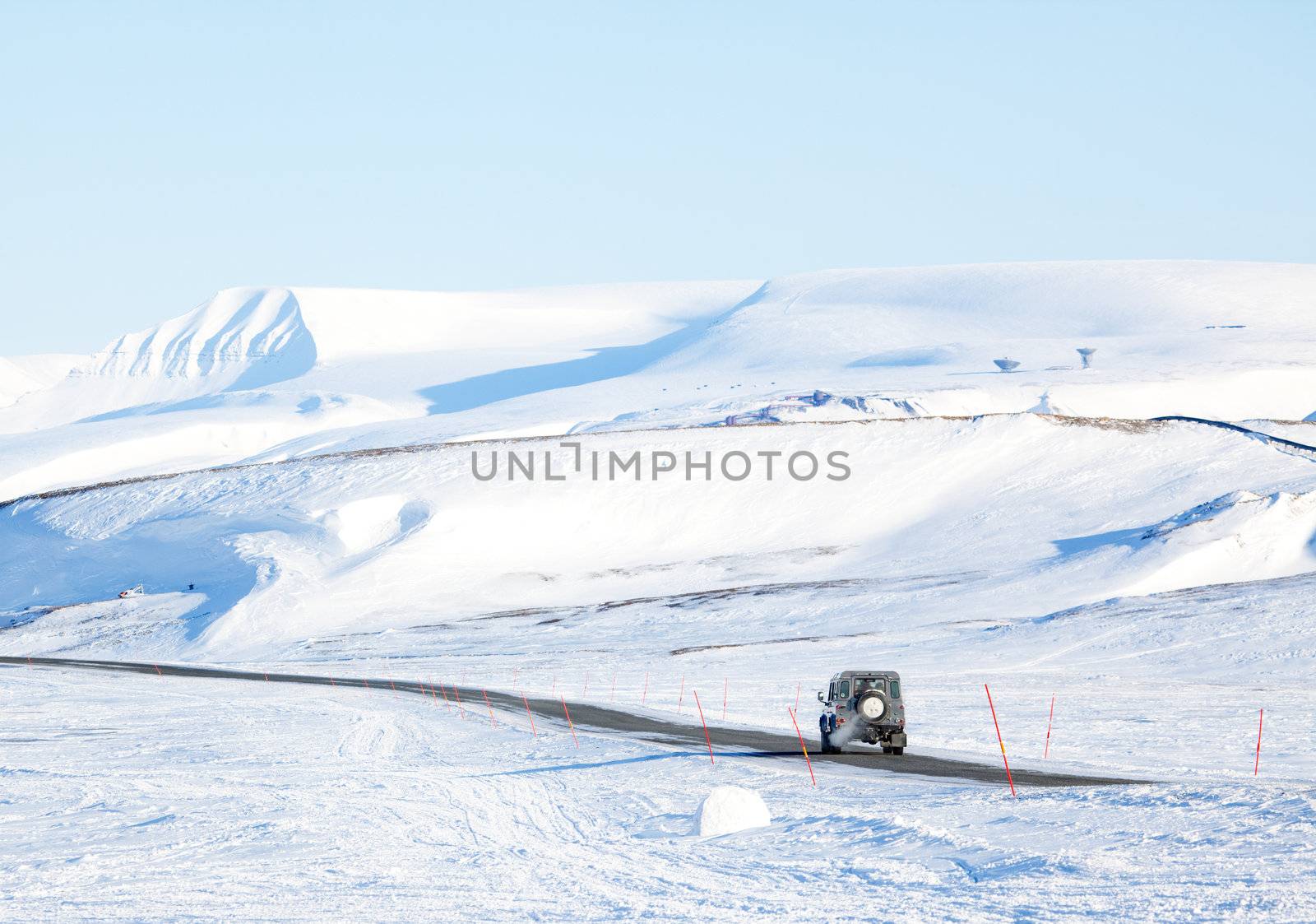 A truck driving on a barren landscape of snow and ice - Svalbard, Norway