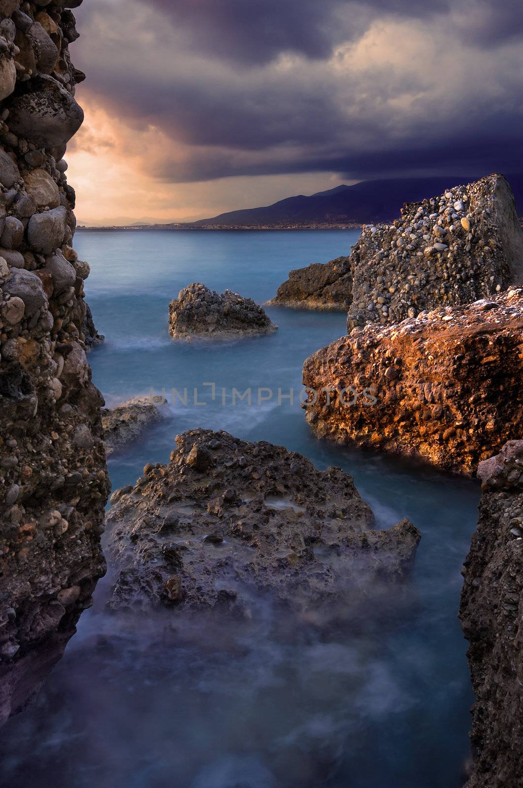 Image shows a rocky seascape during a windy late afternoon