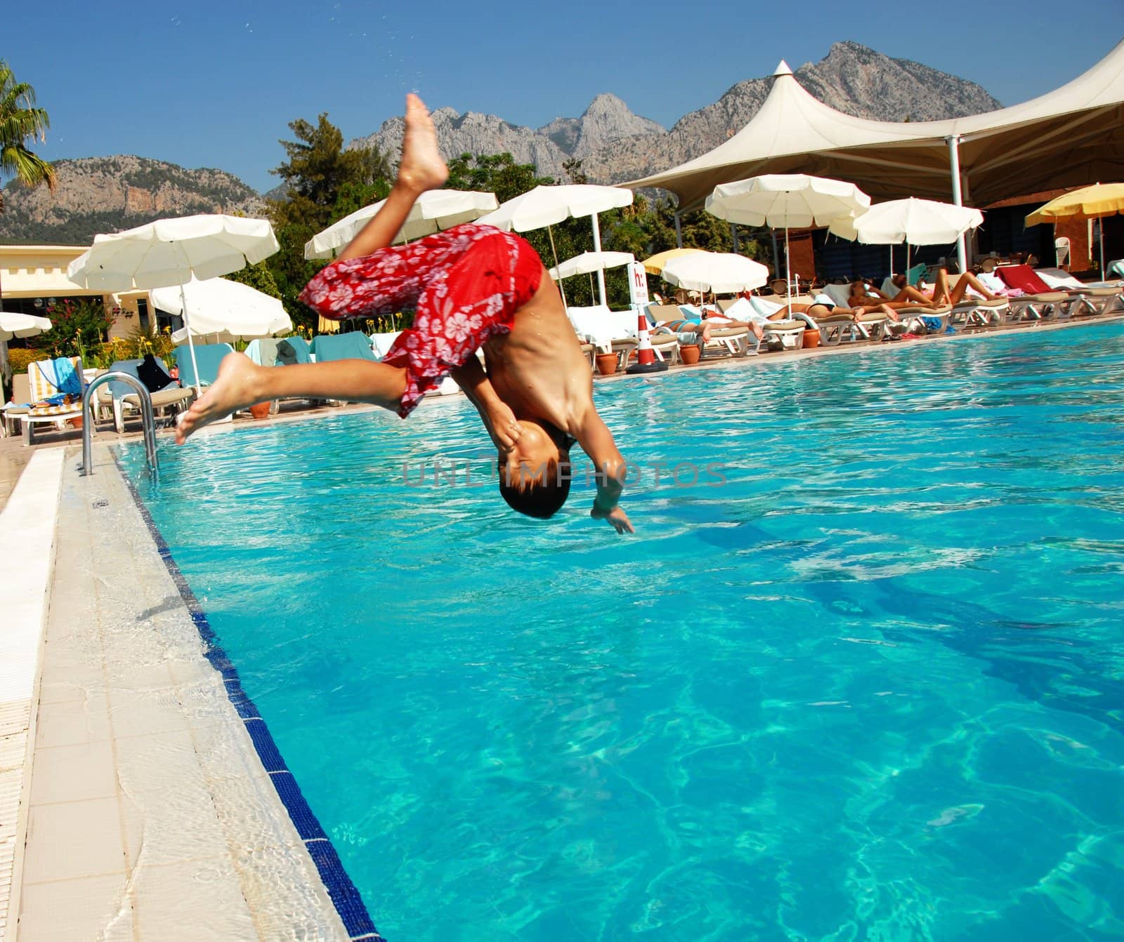 Boy jumping into swimming pool by simply