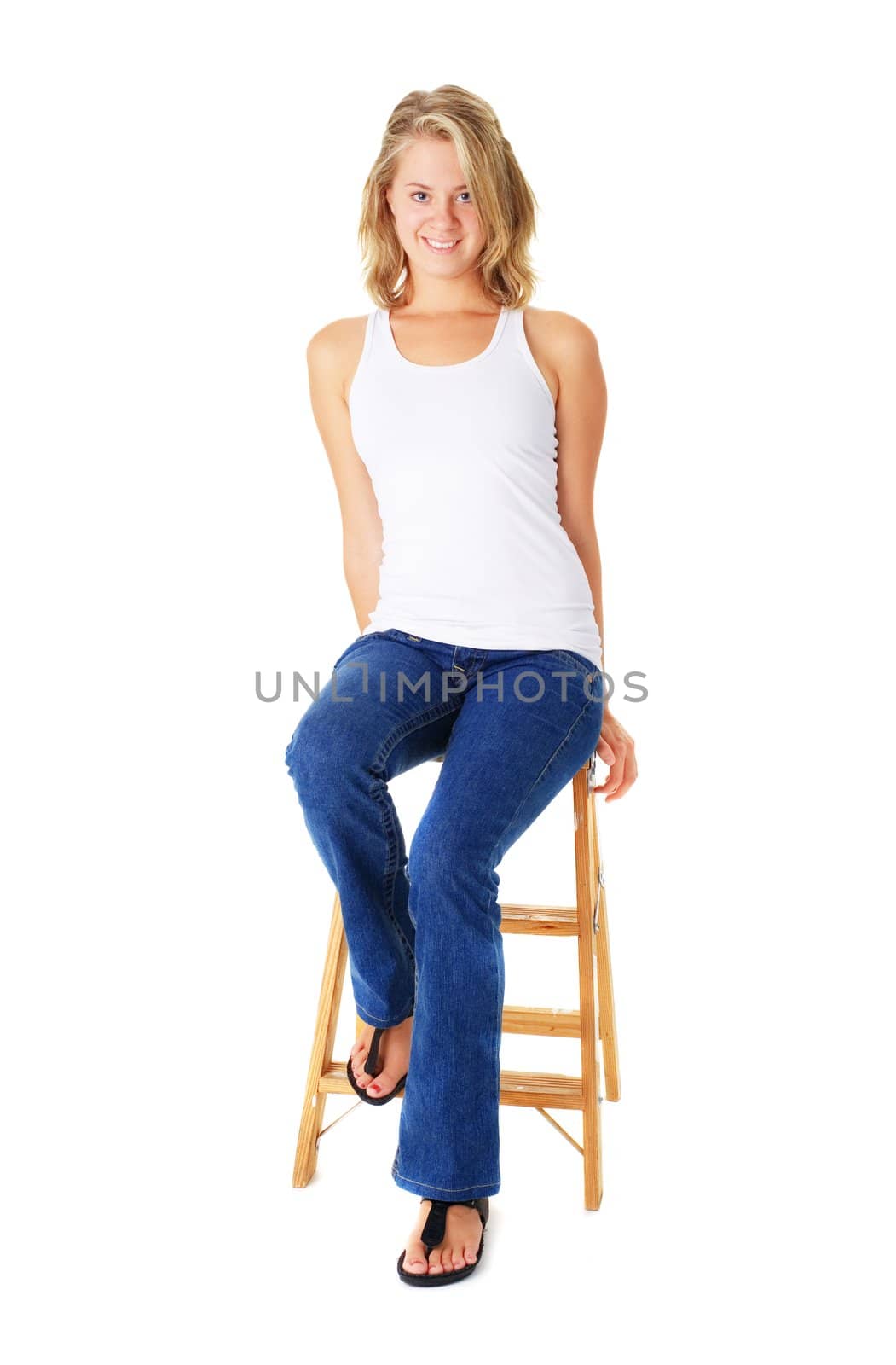 Casual young woman sitting on a small ladder agaisnt white.