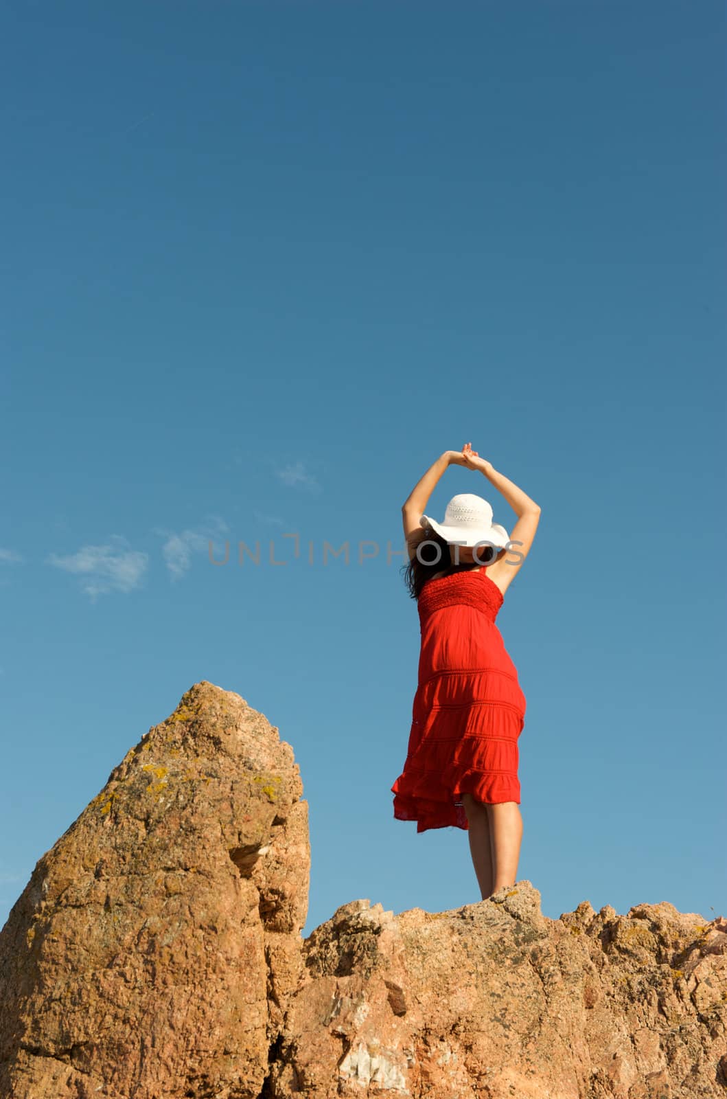 Wonderful pretty woman relaxing on top of the rock at sunset time