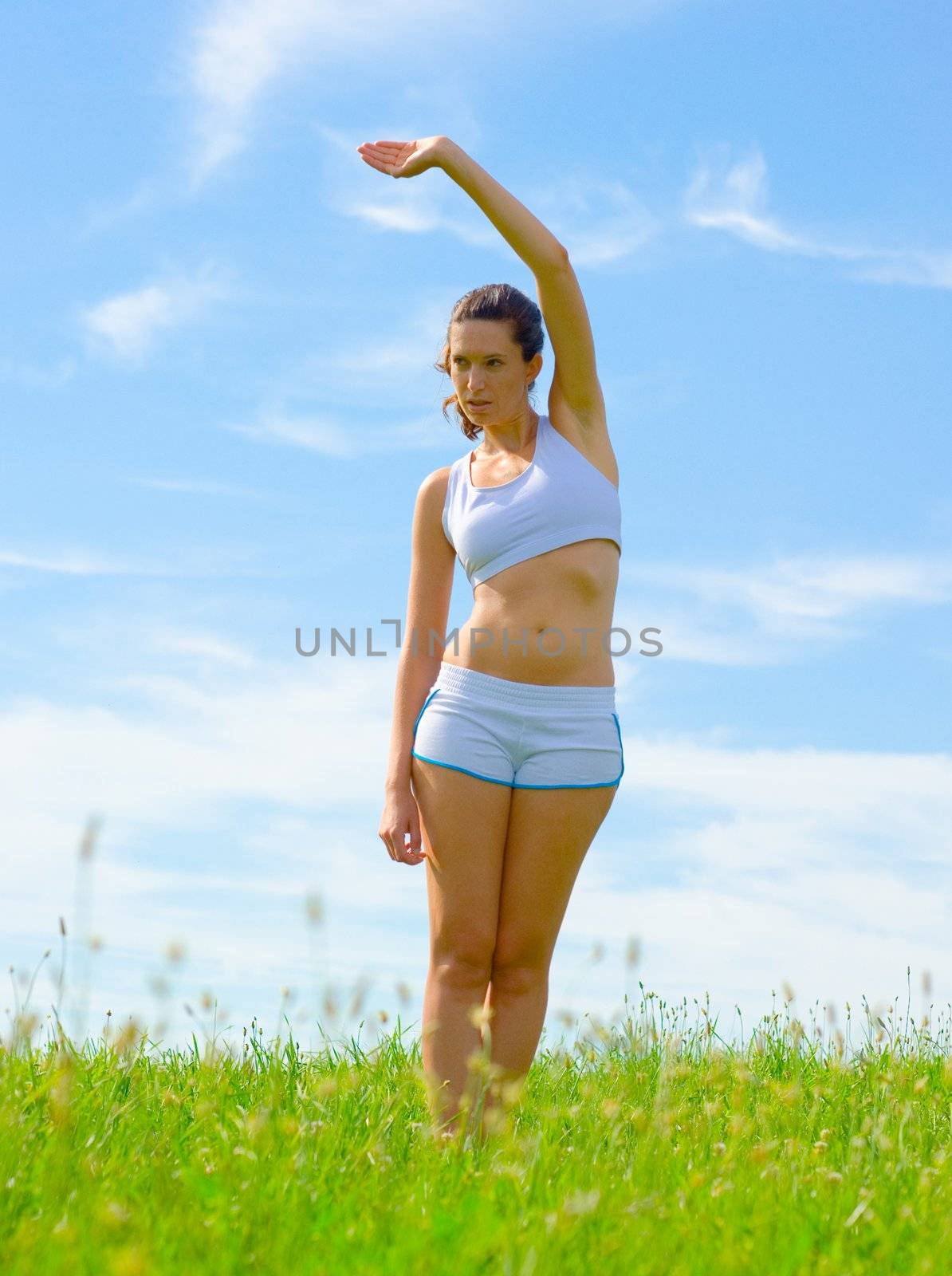 Mature woman athlete practicing in a spring meadow, from a complete series.