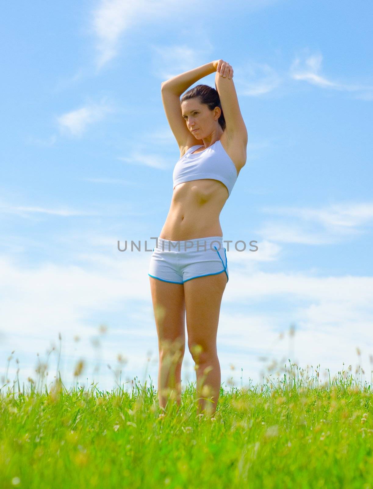 Mature woman athlete practicing in a spring meadow, from a complete series.