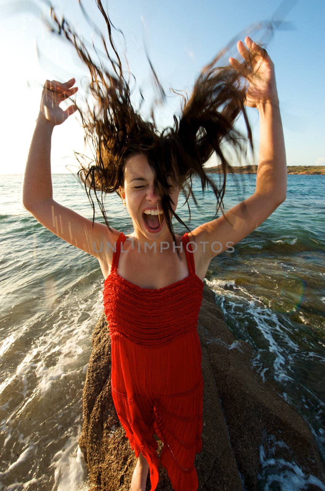 Pretty girl moving her hair on the beach at sunset time