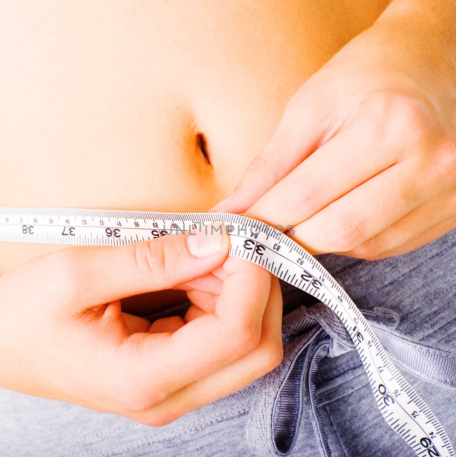 Young woman measuring herself on white, from a complete series of photos.