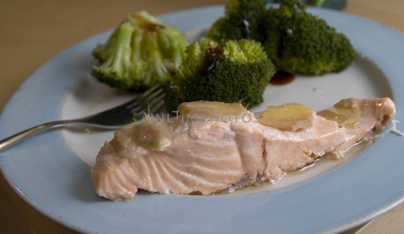 Plate with fish topped with ginger with broccolis on the side