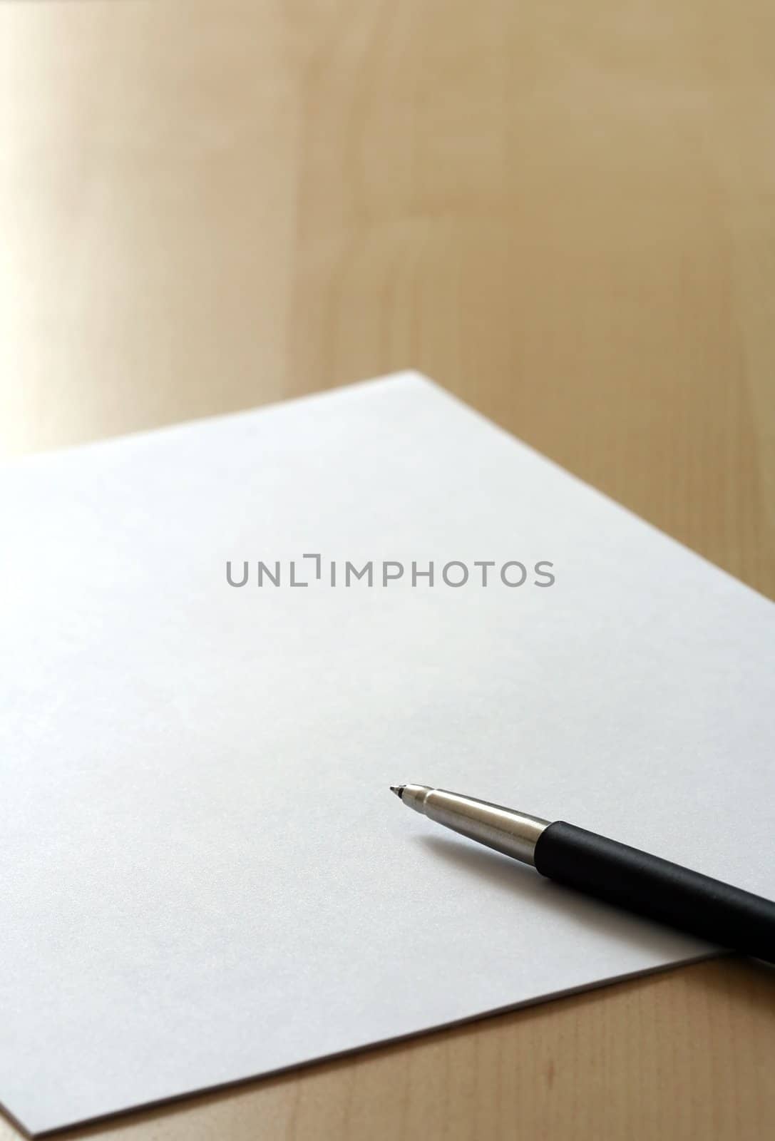 Blank white business paper and a pen on a table