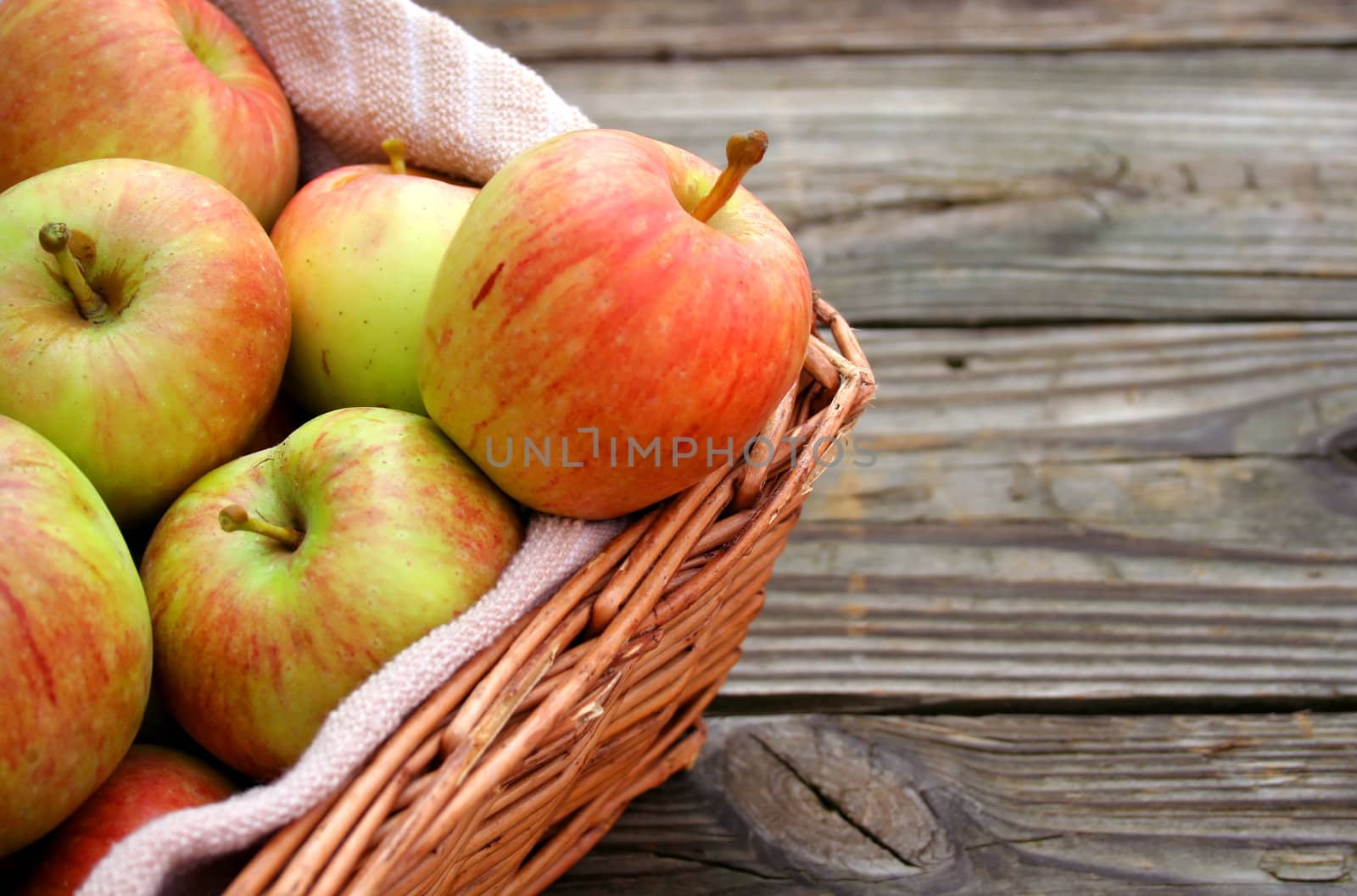 Apples in a basket with wood texture background.