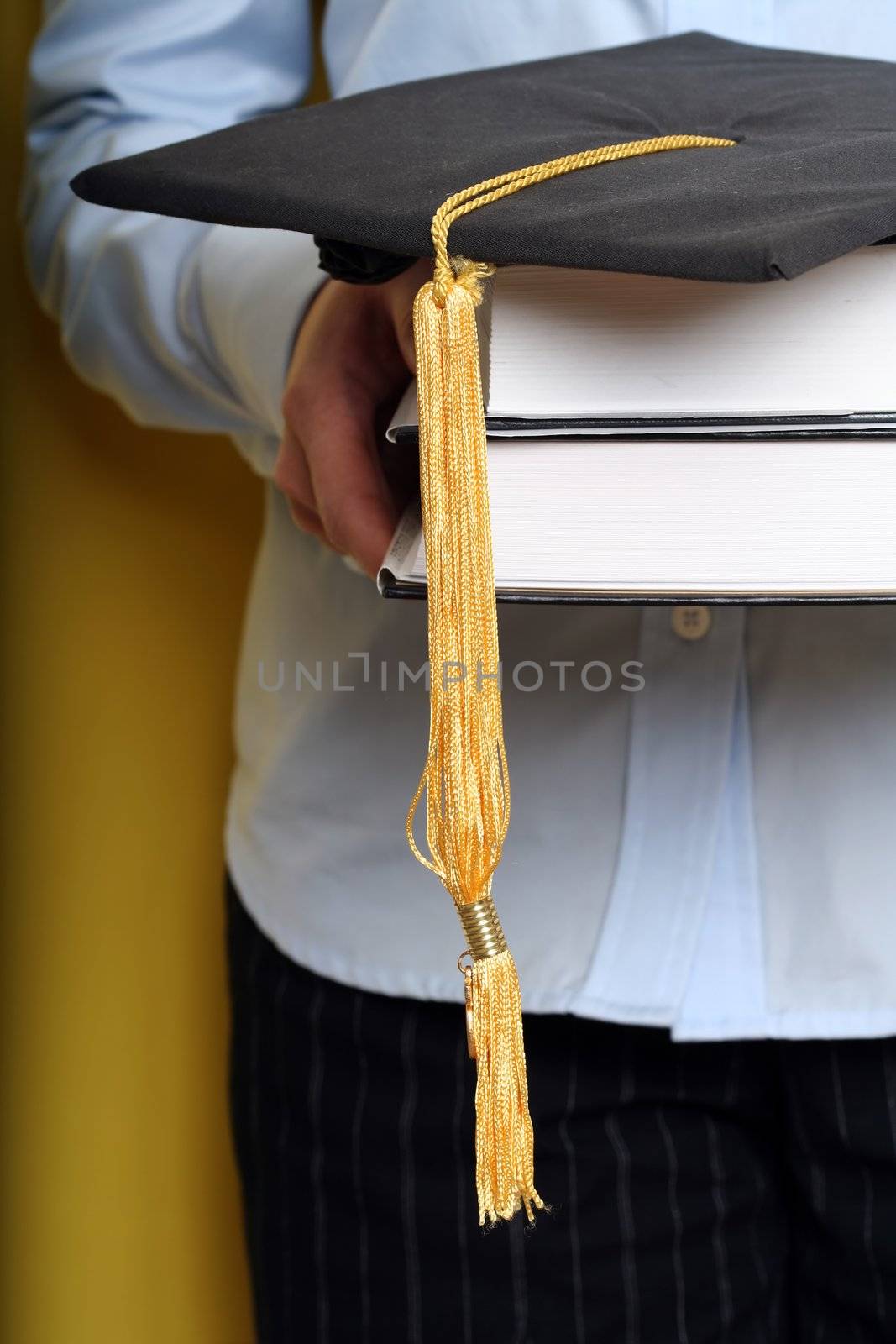 A girl holding books and graduation cap