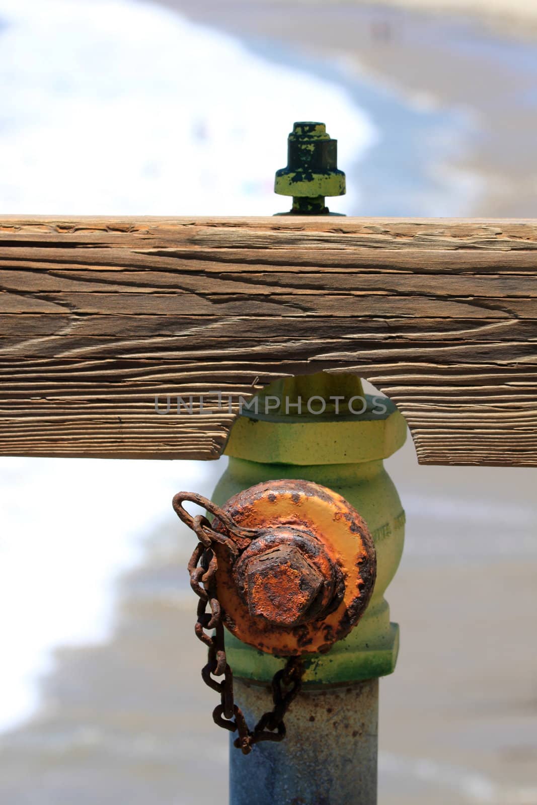 Hydrant on a pier with the beach in the background.