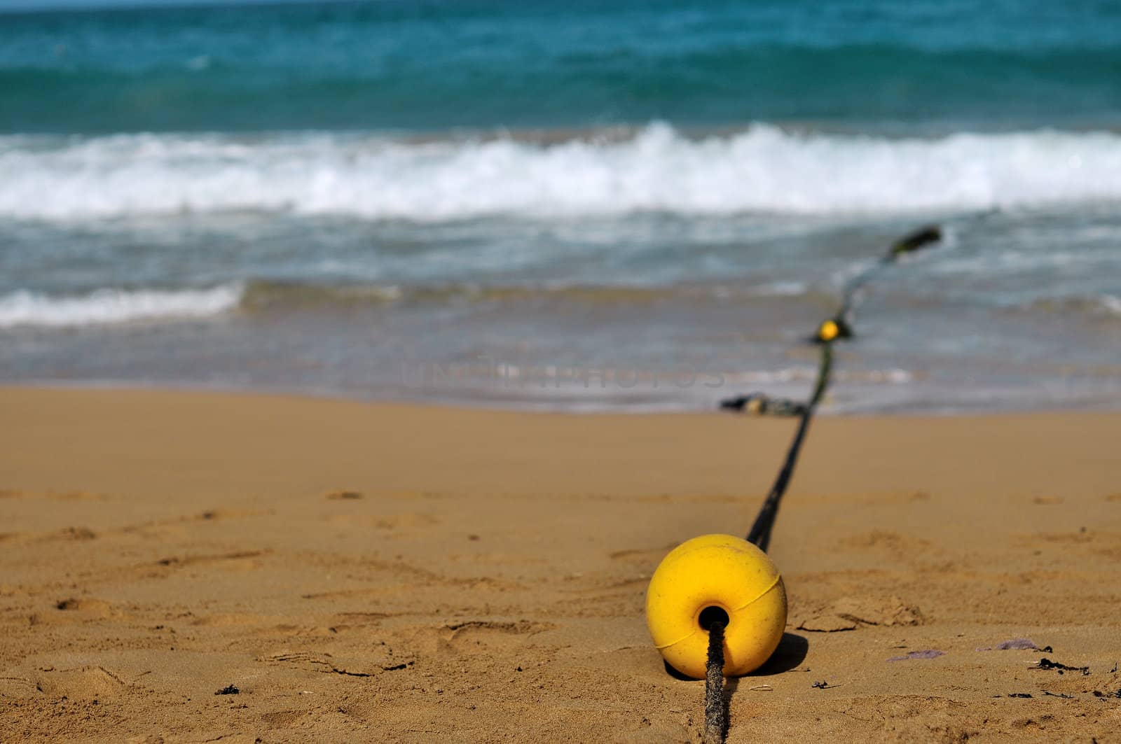 
Yellow float put on rope lies on the sand by the sea