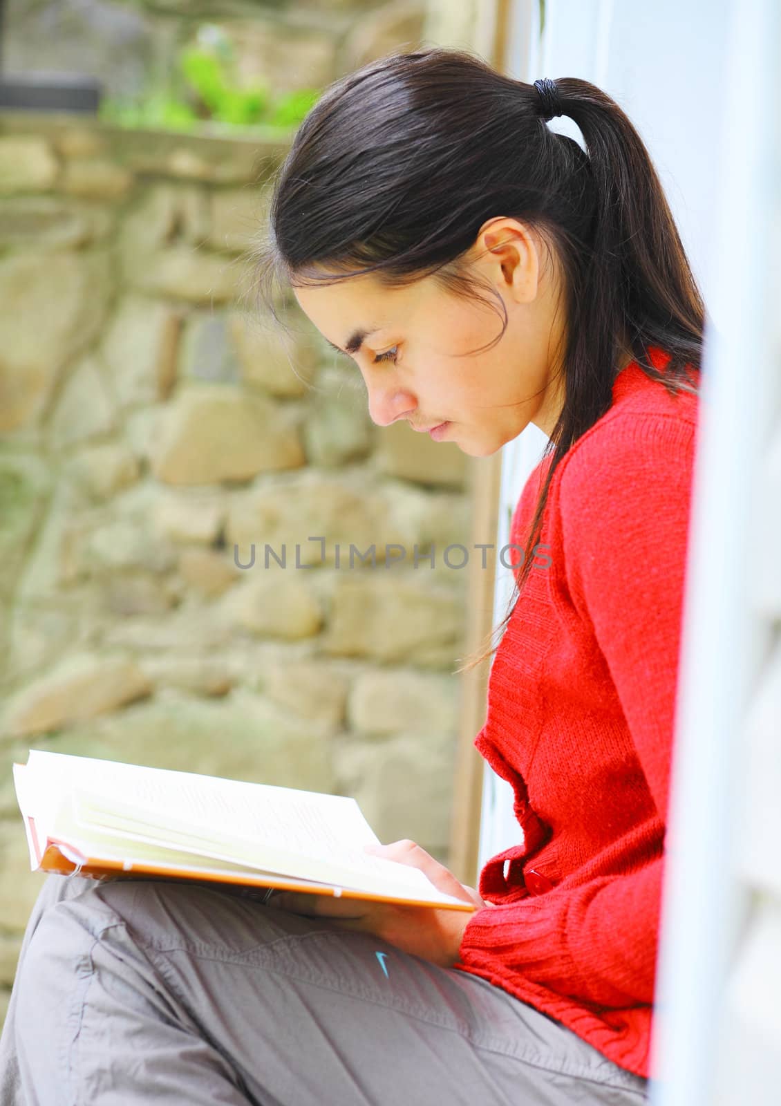 Young woman reading a book outdoors.