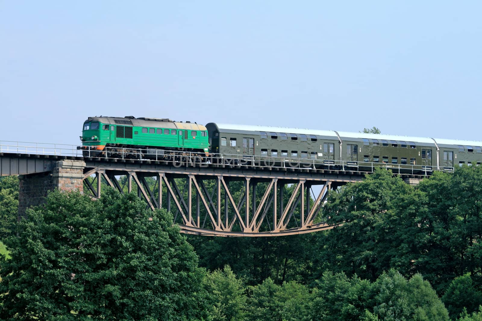 Passenger train passing through the big steel bridge
