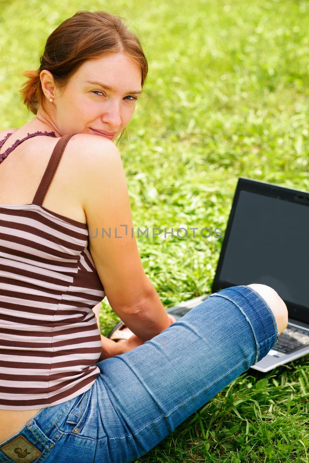 Young woman using her laptop outdoors. by romanshyshak