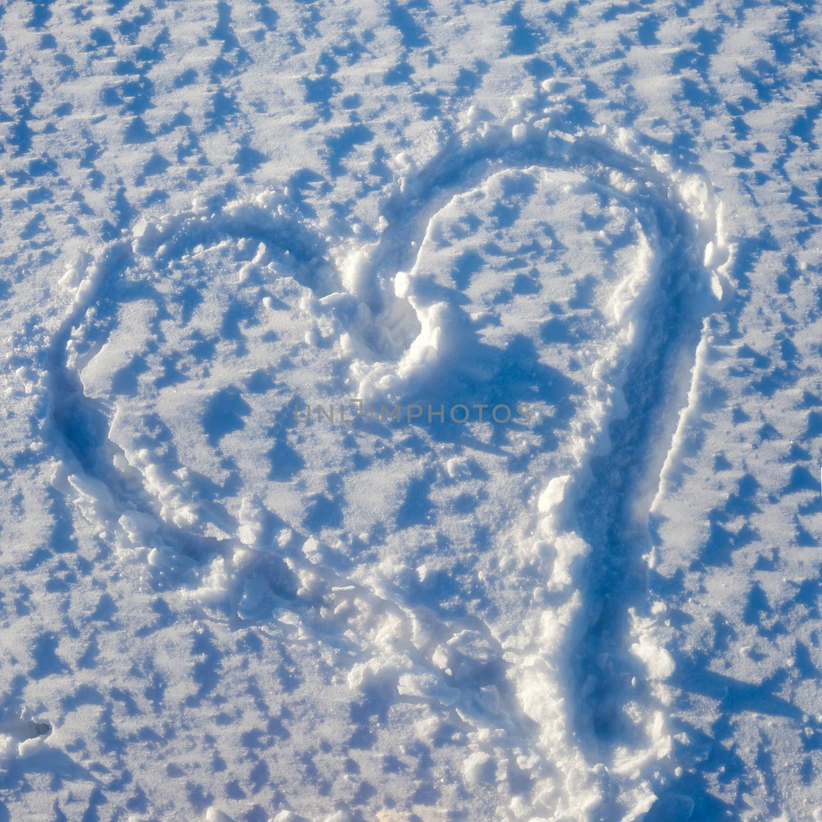 Heart of love sketched on rough snow surface.