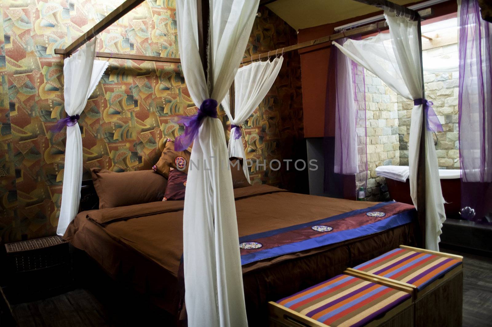 A small boutique hotel bedroom with a four post bed and tub