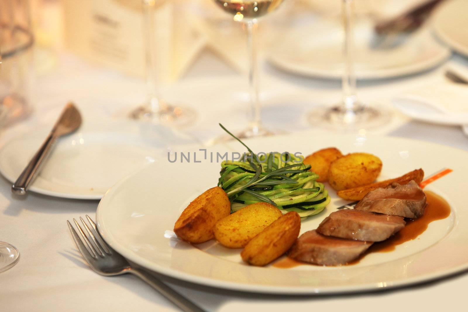 Exclusive dining on a plate consisting of baked potatoes, pork with noodles and sauce