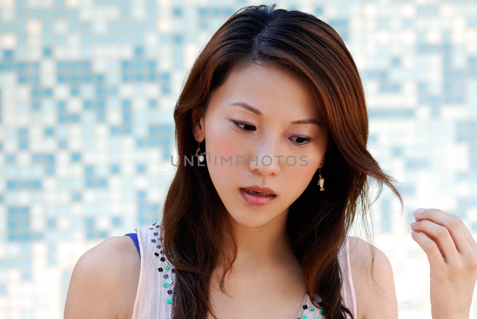 Here is a beautiful Asian lady in front of mosaic and watching.