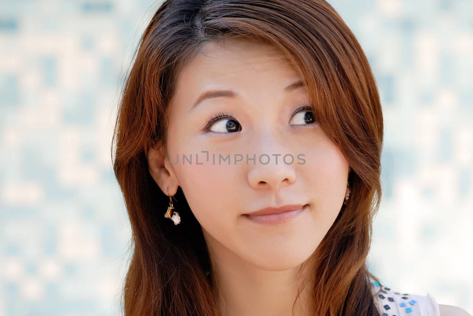 Here is a beautiful Asian lady in front of mosaic and watching.