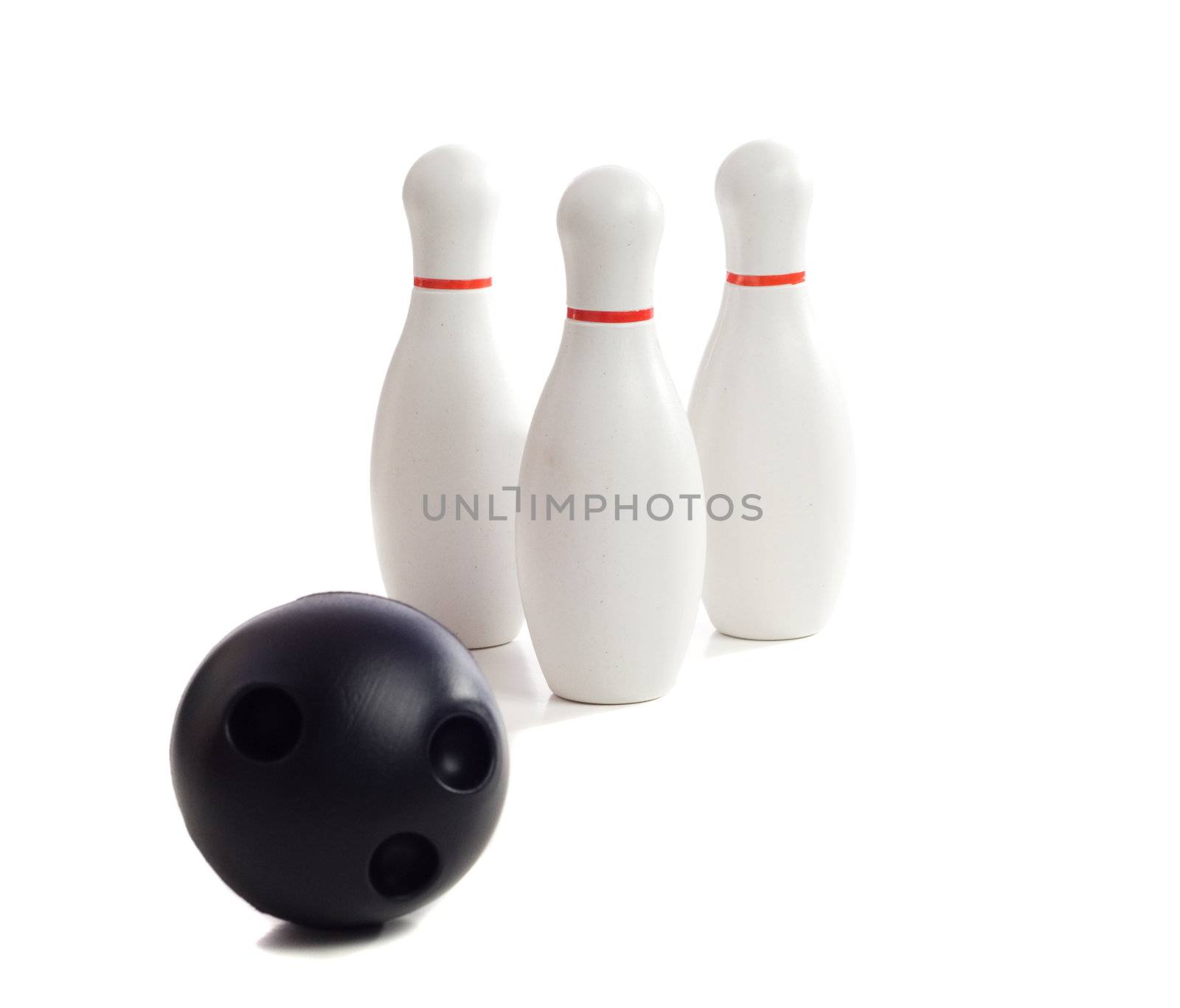 A plastic bowling ball rolling towards three pins, isolated against a white background