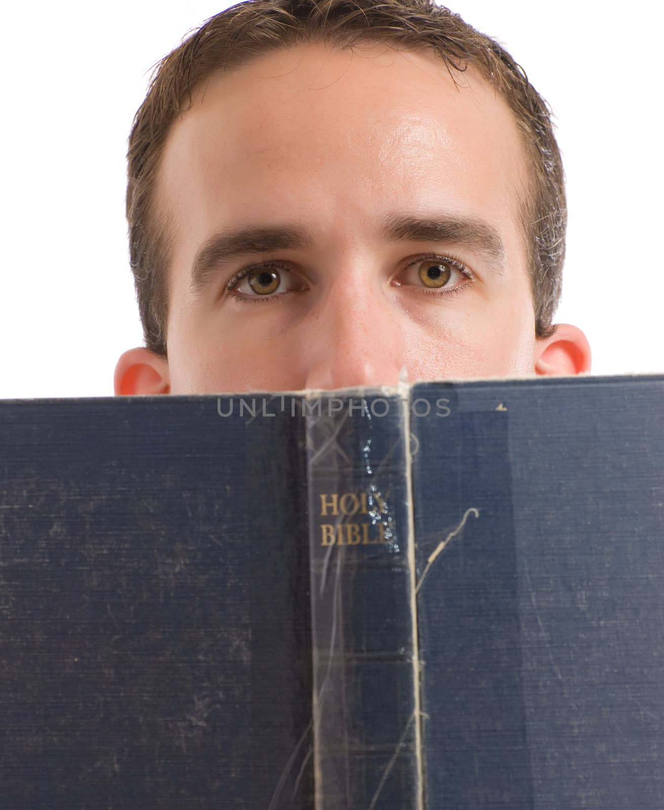 A young man reading his bible with hald his head behind it, isolated against a white background