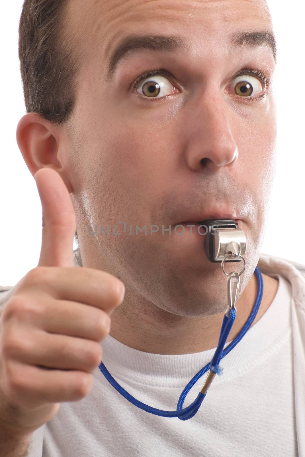 Closeup view of a male coach blowing his whistle and giving a thumbs up to the viewer, isolated against a white background