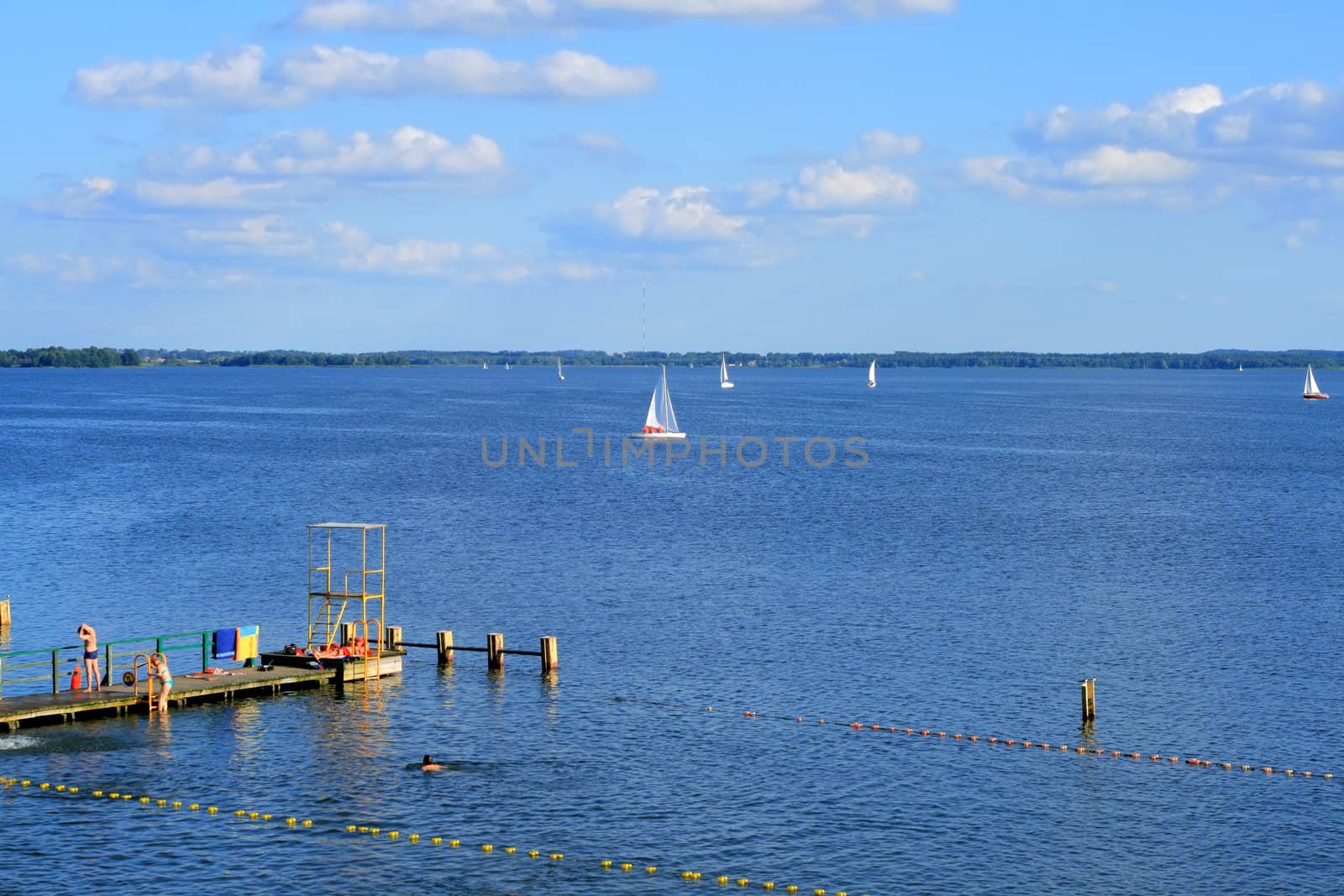 Recreation on the lake. Wooden pier and sailboats.
