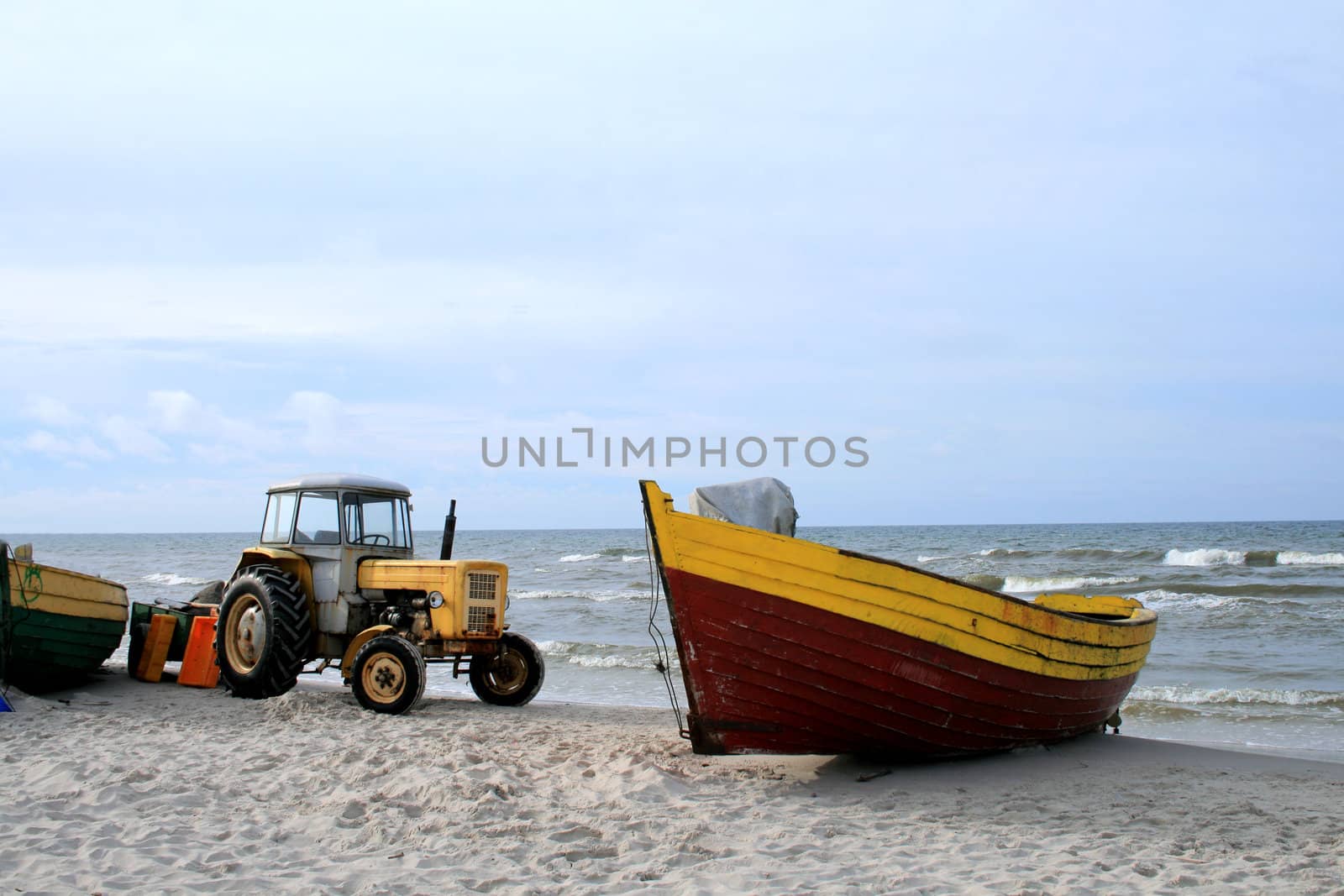 Yellow tractor and wooden boat on the beach
