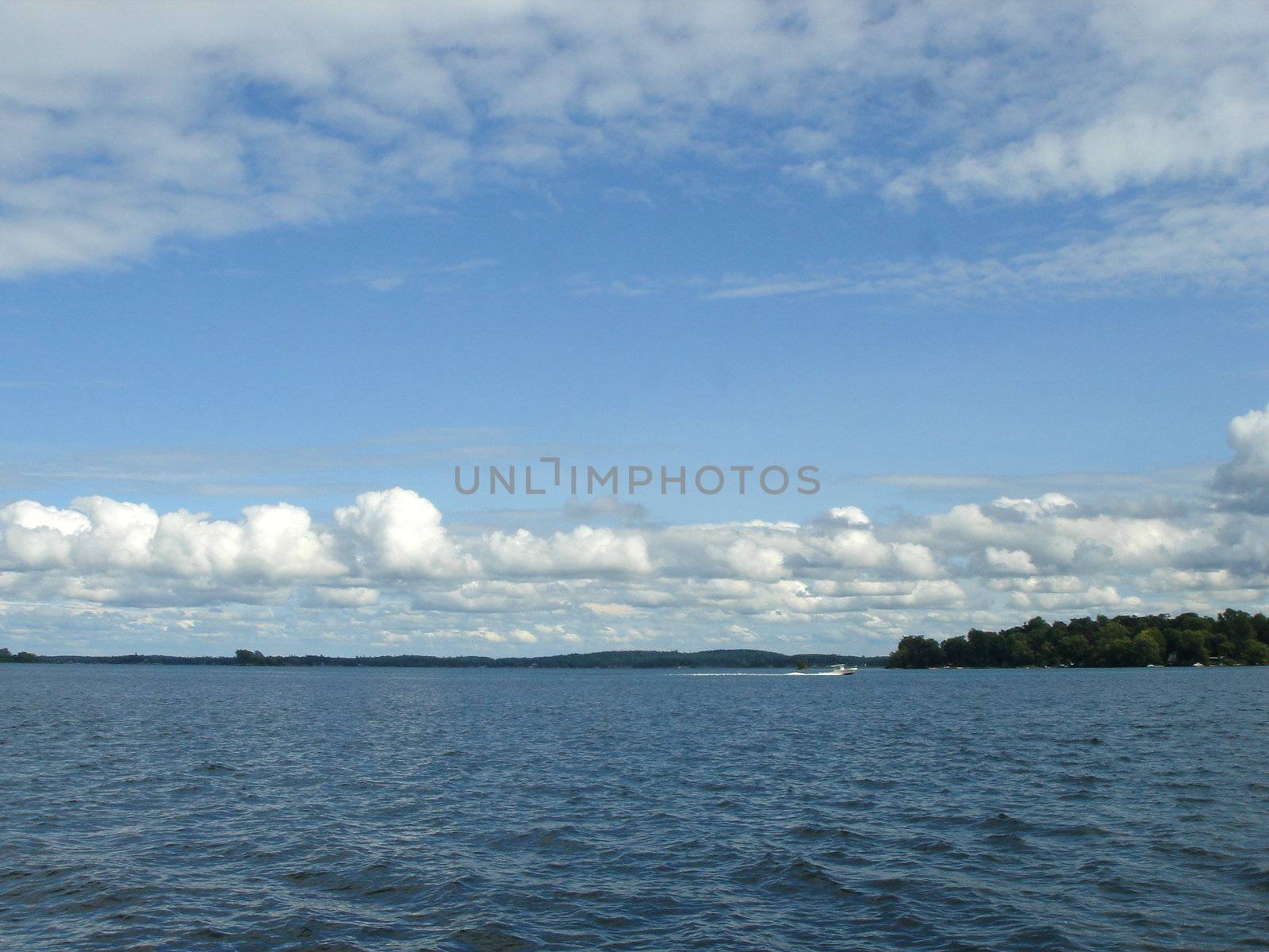 Blue cloudy sky and deep blue lake with island