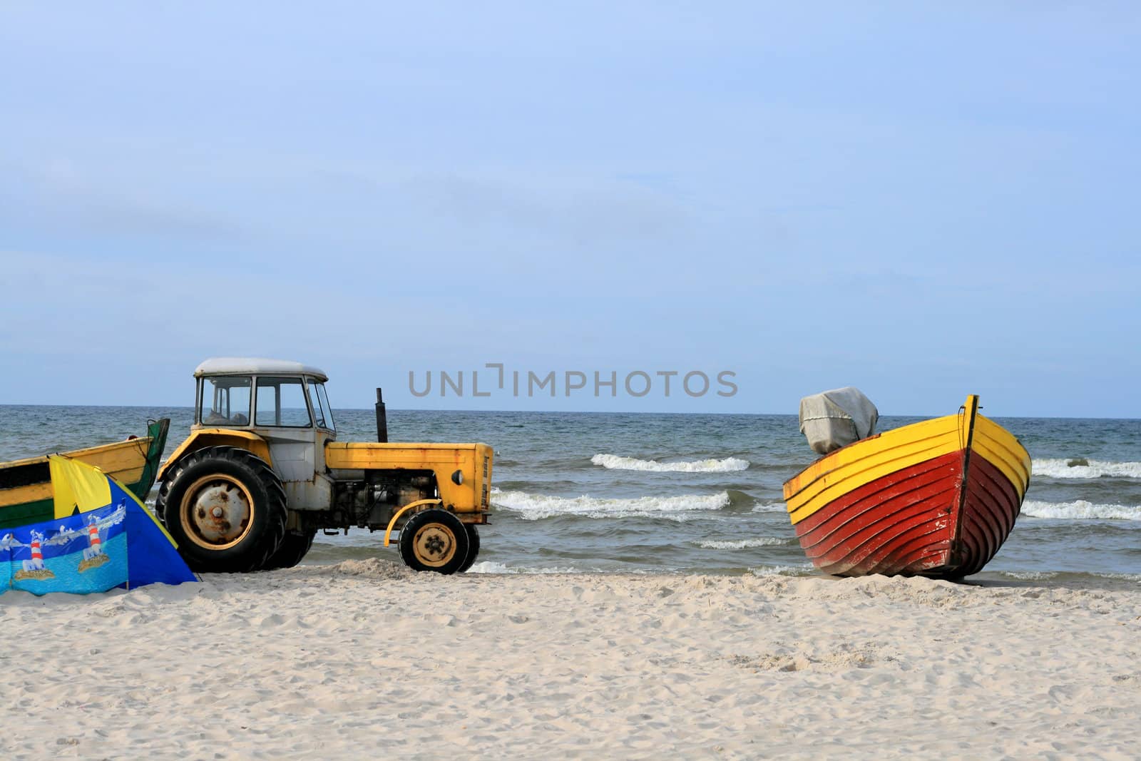 Yellow tractor and wooden boat on the beach
