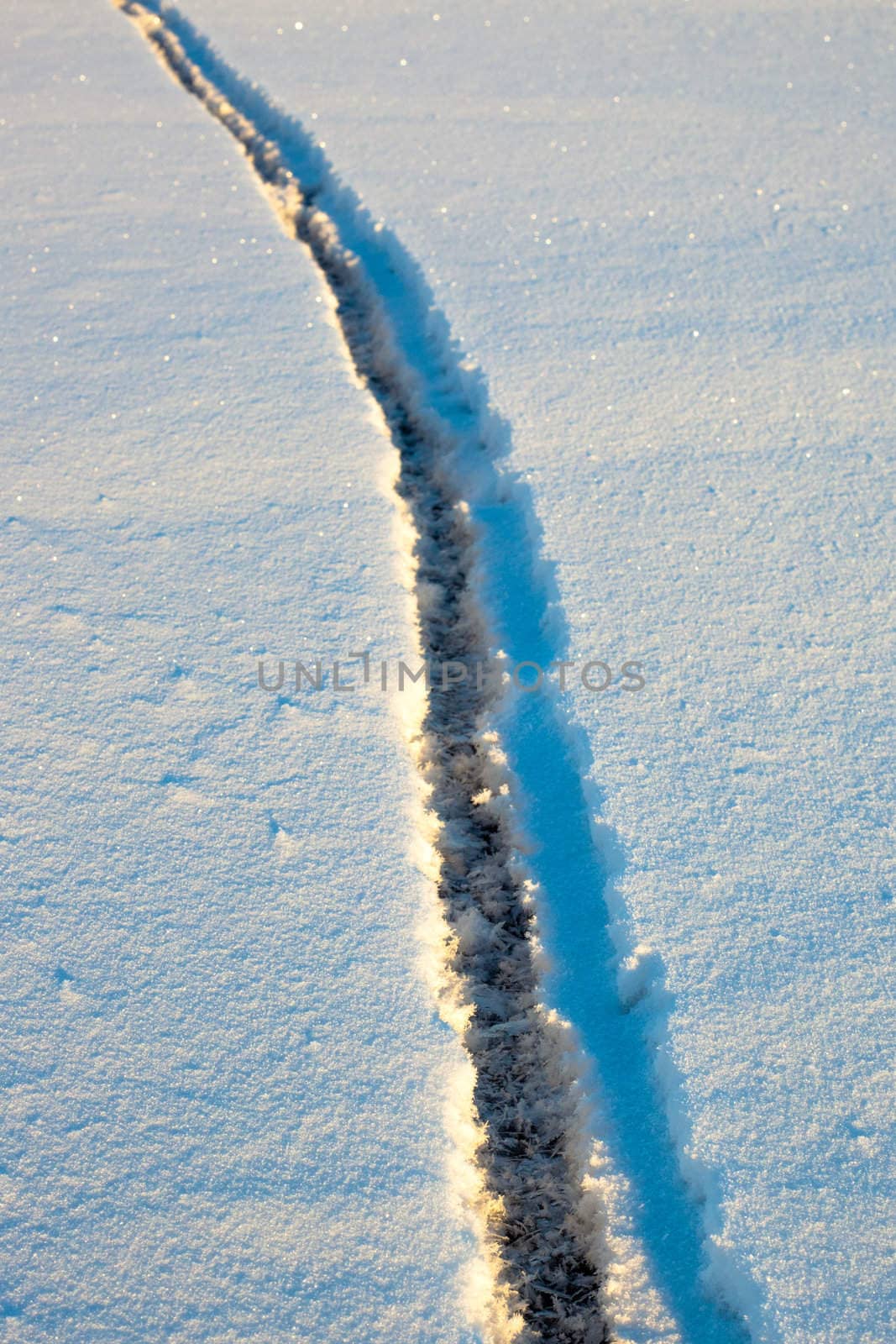 Wide crack in snow-covered ice surface of frozen lake.