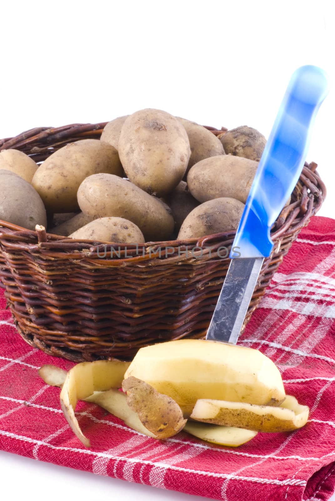 Basket with potatoes standing on red cloth, isolated on white.